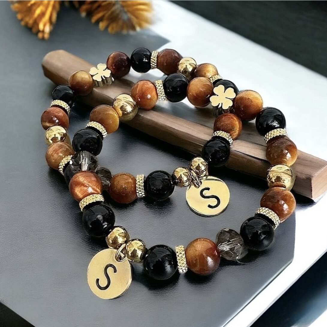 A bracelet made from natural stones, featuring a gold four-leaf clover and a letter of your choice