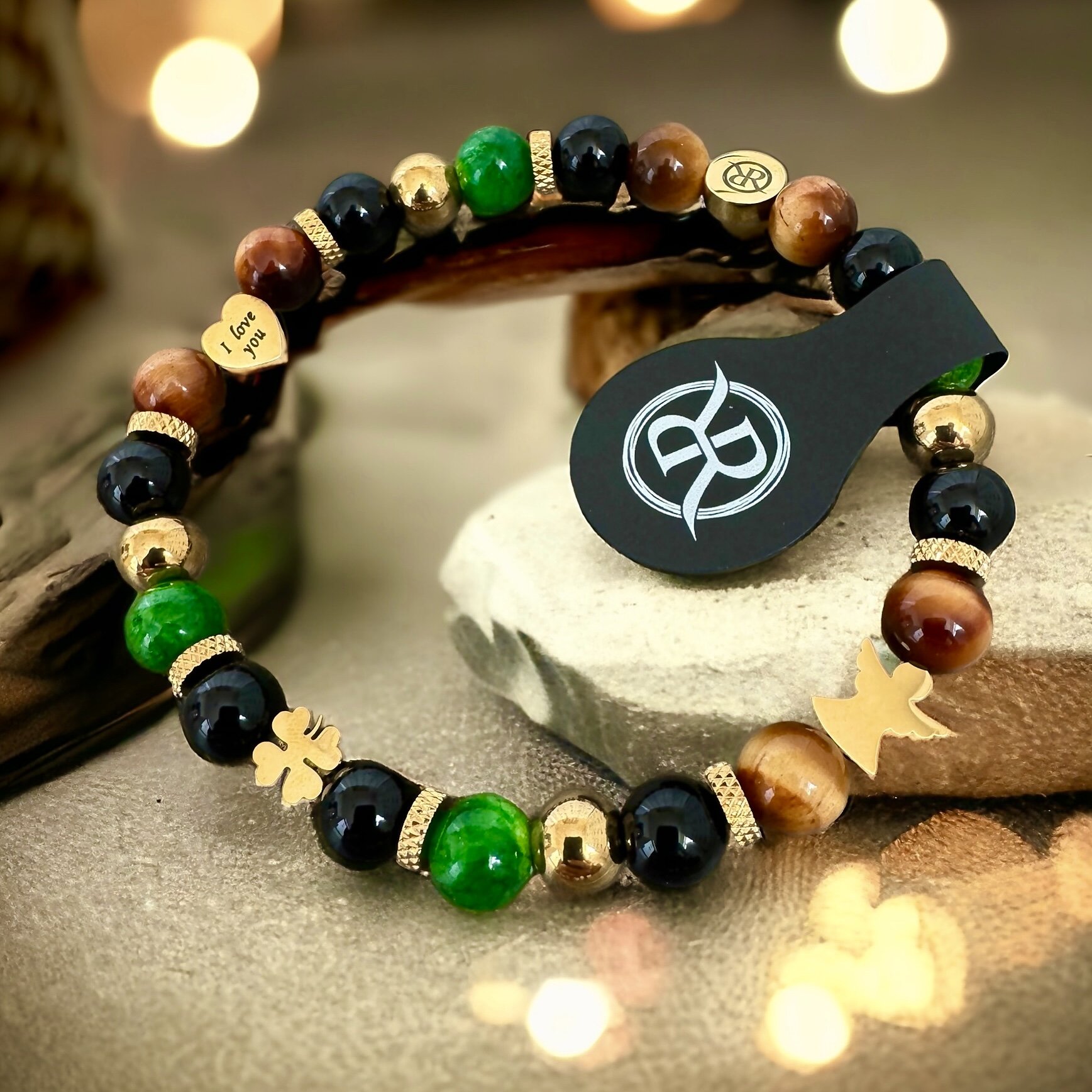 Bracelet made of natural stones with golden four-leaf clover, heart with engraving and cherub