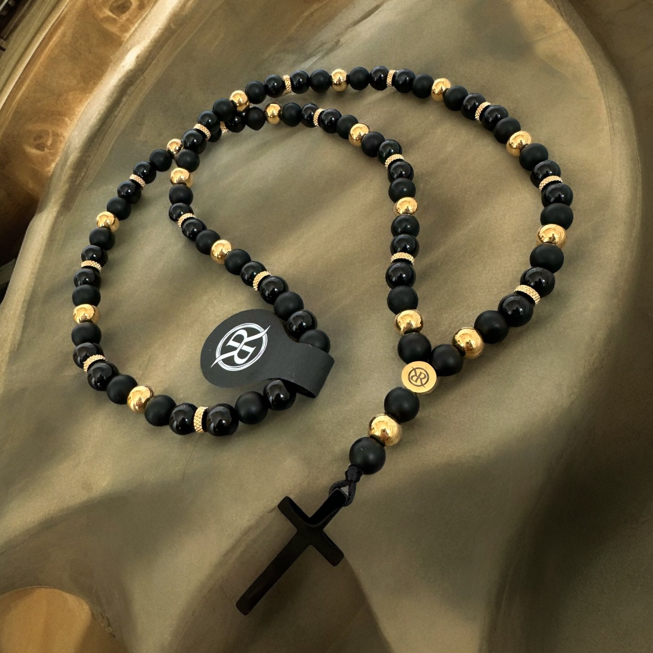 Necklace in the shape of a rosary made of natural stones with a black cross